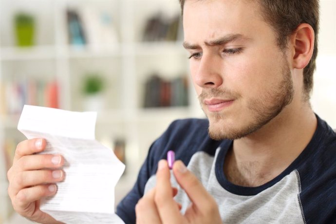 Archivo - Hombre mirando el prospecto de un medicamento.