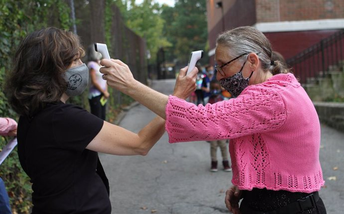 Archivo - 29 September 2020, US, New York: Teacher Marissa Maher (L) and parent Coordinator Nina Velasquez check each other temperature on the first day of school. New York City elementary schools welcomed students back to the classroom on Tuesday, whil