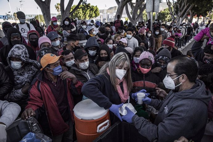 Archivo - 19 February 2021, Mexico, Tijuana: Food and water are distributed to waiting asylum seekers at the El Chaparral between Mexico and the US. Starting from today, the new US administration under US President Joe Biden will gradually allow the ent