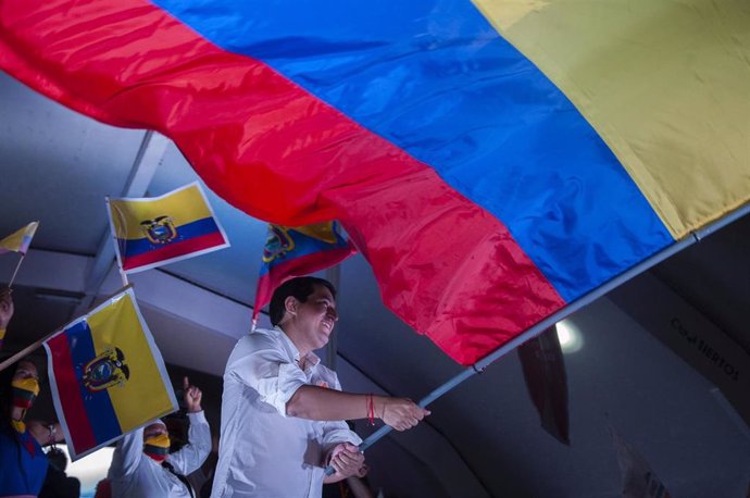 08 April 2021, Ecuador, Quito: Andres Arauz, the presidential candidate in Ecuador, waves a large national flag on stage at the end of his campaign. The runoff between leftist candidate Arauz and conservative banker Lasso is scheduled to take place on 1