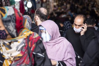 Archivo - Una mujer camina por la calle con mascarilla y pantalla facial en Teherán.