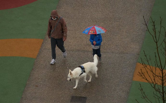 Archivo - Dos personas se refugian con un paraguas de la lluvia en Vitoria