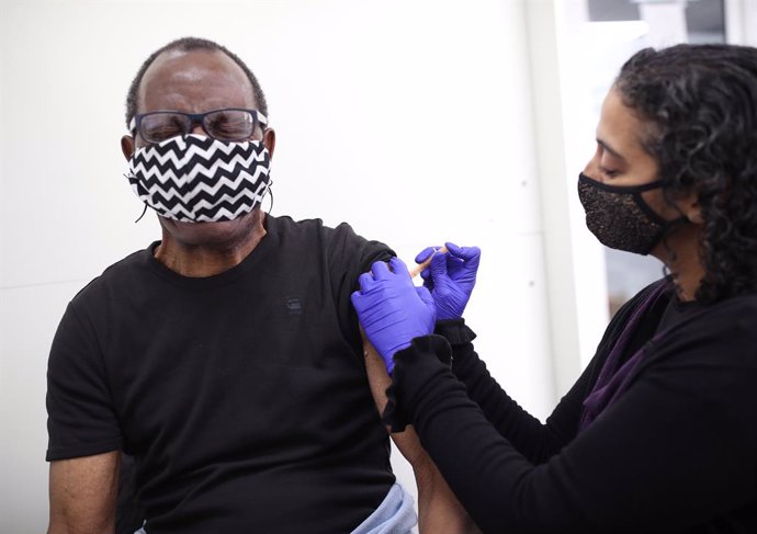 09 April 2021, United Kingdom, London: Pharmacist Asha Fowells (R) vaccinates Paul Jinadu,79, with his second dose of the Oxford/AstraZeneca coronavirus vaccine, at Copes Pharmacy and Travel Clinic in Streatham, south London. Photo: Yui Mok/PA Wire/dpa