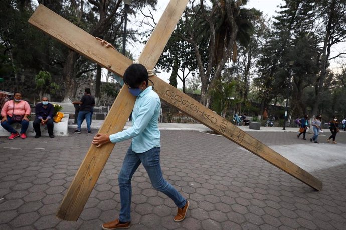 14 March 2021, Mexico, Mexico City: A man carries a big wooden cross at the church of La Cuevita during the first rehearsal with the cast of the Passion of Christ play which will be broadcasted on the internet for Holy Week due to the coronavirus (Covid