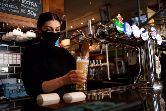 12 April 2021, United Kingdom, Birmingham: A waitress at the Figure of Eight pub pours a glass of beer. Shops, hairdressers and outdoor restaurants are now allowed to reopen following the easing of the coronavirus restrictions across England. Photo: Jac