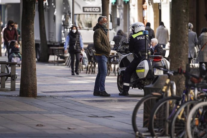 Un hombre habla con un policía local en una calle céntrica de Vitoria