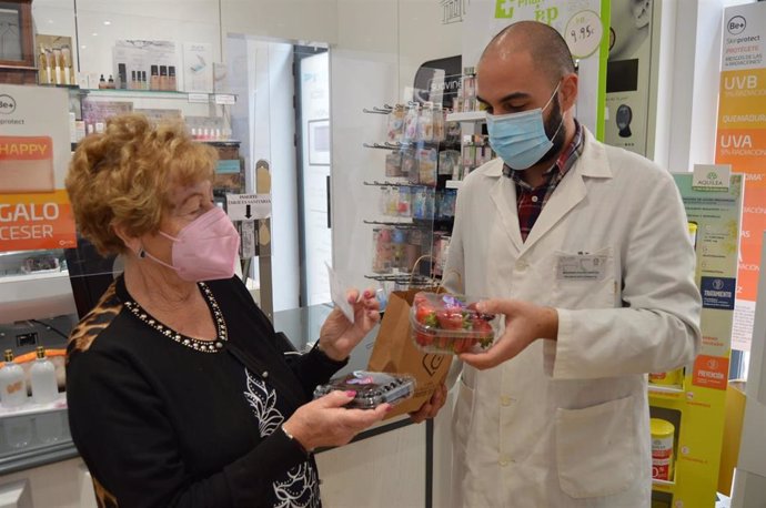Una onubense recoge tarrinas de frutos rojos en una farmacia de la capital.