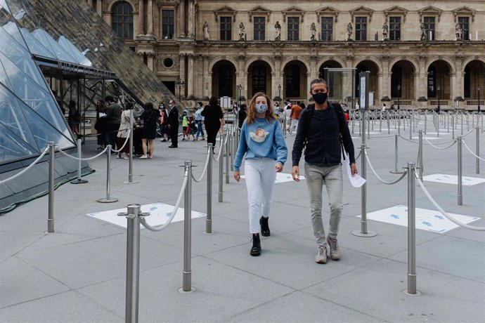 Archivo - Personas con mascarillas junto al Museo del Louvre de París