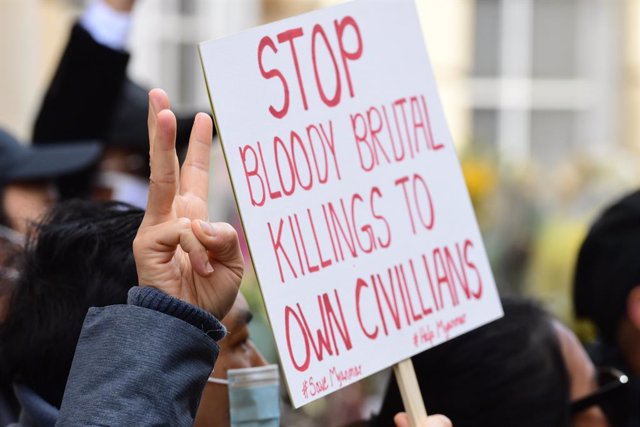 08 April 2021, United Kingdom, London: Protesters shows a three-fingered sign of resistance while holding a placard during a protest outside the Myanmar embassy, which Myanmar's former ambassador to the UK, Kyaw Zwar Minn, has been barred from entering.