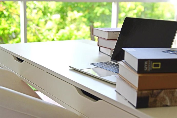 Archivo - Un escritorio con un ordenador portátil y varios libros