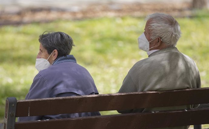 Un hombre y una mujer mayores, sentados en un banco y con mascarilla, en el Parque del Manzanares