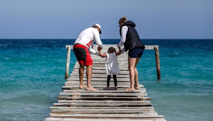 Una familia en una pasarela de madera en playa de Muro.