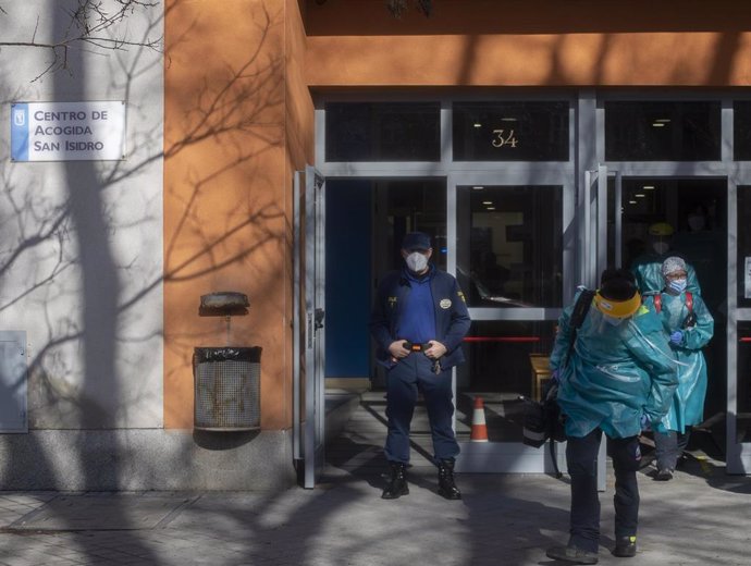 Archivo - Un empleado de seguridad vigila una de las puertas del centro de acogida San Isidro, en Madrid.