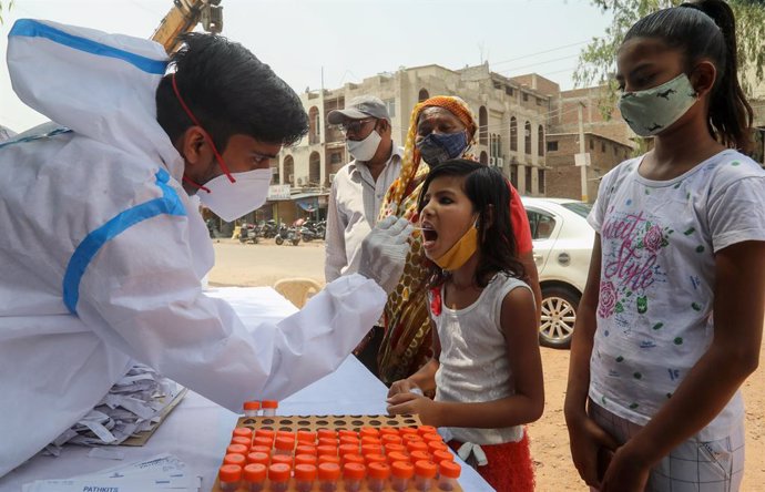 12 April 2021, India, New Delhi: A healthcare worker takes a mouth swab from a child for coronavirus (Covid-19) test at the roadside testing centre at Wazirpur Industrial Area in New Delhi. India overtakes Brazil as the country with the second-largest C