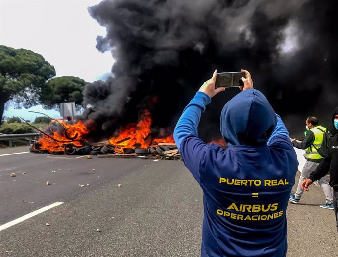 Un trabajador fotografía el incendio provocado por parte de la plantilla de la factoría de Airbus de Puerto Real en la autovía CA- 35 que da acceso a los puentes de la Bahía de Cádiz,  como protesta por el cierre de la planta. Puerto Real (Cádiz) a 14 d