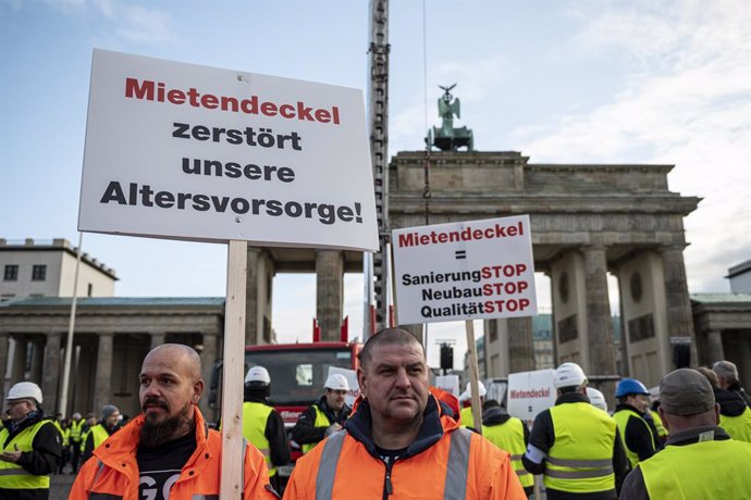 Archivo - 09 December 2019, Berlin: People hold placards in front of the Brandenburg Gate during a rally organized by an alliance of the Berlin construction and housing industry and landlords against rent caps, proposed by the state of Berlin to set an 