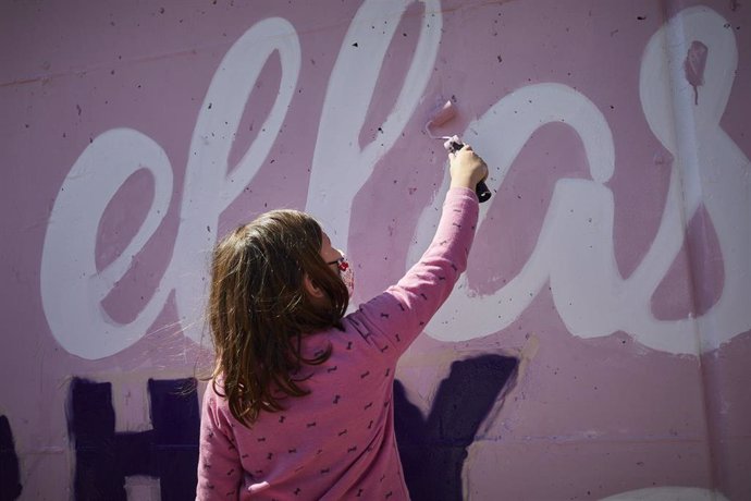 Archivo - Una niña participa en la tarea de pintar de nuevo el mural feminista de Unlogic Crew junto a la estación de Getafe Central, en Getafe, Madrid (España), a 14 de marzo de 2021. Los creadores del mural feminista de Ciudad Lineal, el colectivo Unl