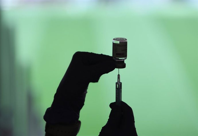 Un profesional sanitaria sostiene una jeringuilla y un vial con la vacuna del Covid-19, en un dispositivo instalado en el Estadio Wanda Metropolitano, en Madrid (España), a 30 de marzo de 2021. La Comunidad de Madrid ha comenzado a vacunar este martes f