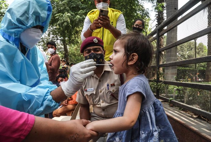 15 April 2021, India, New Delhi: A healthcare worker in protective suit collects a mouth swab sample from a kid for a COVID-19 RT-PCR test outside the DT City Centre Mall. Photo: Naveen Sharma/SOPA Images via ZUMA Wire/dpa