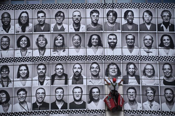 Archivo - dpatop - 08 July 2020, France, Paris: A worker glues portraits of health workers on the facade of the Opera Bastille, during an initiative organized by the community "#ProtegeTonSoignant" (Protect your health care workers) to honour health car