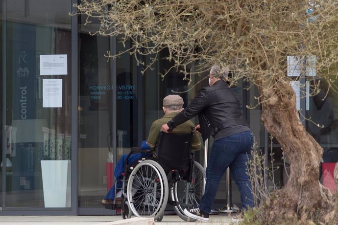 Una mujer pasea junto a un anciano en silla de ruedas hacia la residencia Albertia, a 17 de abril de 2021, en Lugo, Galicia (España). Una de las nuevas medidas incluidas en la desescalada de Galicia consiste en la ampliación de las posibilidades de visi