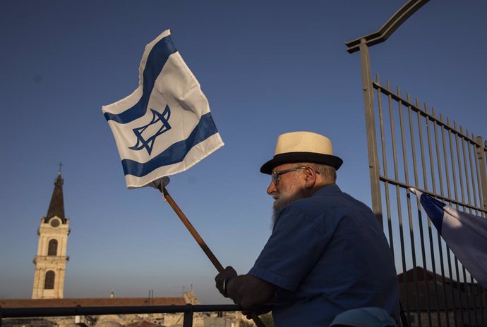 Archivo - 21 May 2020, Israel, Jerusalem: A man holds the Israeli national flag as he takes part in the annual flag parade to mark Jerusalem day celebrations. Jerusalem Day is an Israeli holiday that commemorates the establishment of Israeli control ove