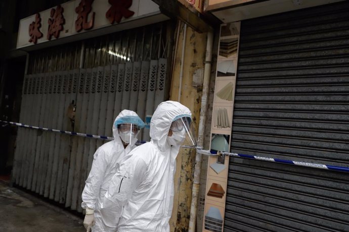 Archivo - 23 January 2021, China, Hong Kong: Sanitizing team stand in front of closed shops in Yau Tsim Mong district where unprecedented lockdown has been declared early this morning by Hong Kong government in order to carry out compulsory coronavirus 