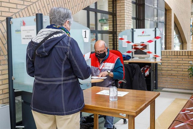 Voluntarios ayudan a realizar la autocita a personas mayores en el centro cívico Río Ebro de Zaragoza para la vacuna conta la COVID-19