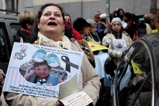 Archivo - Una mujer sujeta un cartel en el que se ve la foto de una de las madres de bebés robados.