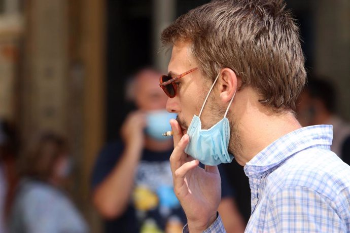 Archivo - Una persona fuma en la calle durante el primer día de la prohibición de realizarlo en la vía pública en Andalucía si no existe una distancia de dos metros de separación con otras personas para evitar contagios de Covid-19. 