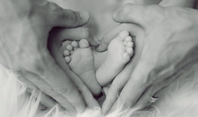 Los pies de un bebé entre las manos de sus padres