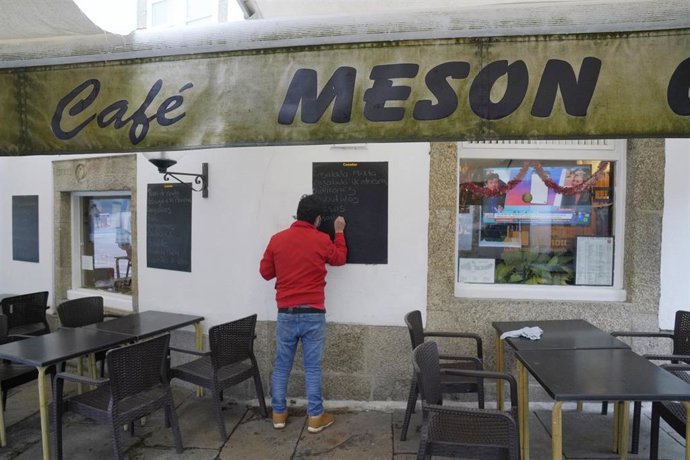 Archivo - Un hombre escribe en la pizarra de un mesón, en Santiago de Compostela, A Coruña, Galicia (España), a 4 de diciembre de 2020. Hoy se reabre la hostelería en toda Galicia, aunque en distinto grado en función de los datos de los contagios de cor