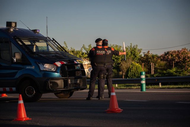 Archivo - Dos Mossos d'Esquadra controlan un acceso en carrtera por las restricciones de movilidad decretadas por el coronavirus (Archivo)