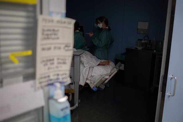 Archivo - Personal sanitario visita a un paciente ingresado en la Unidad de Cuidados Intensivos.