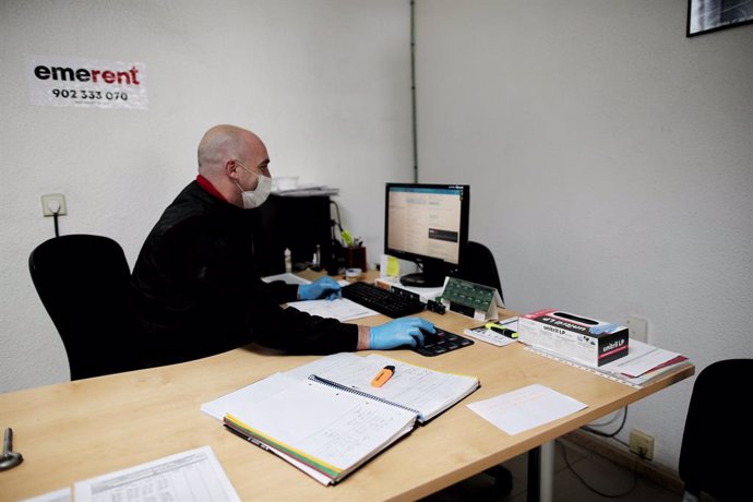Archivo - Un operario protegido con una mascarilla y guantes trabaja desde el ordenador en la empresa EmeRent de alquiler de maquinaria de obra en el segundo día de la reactivación de la actividad laboral no esencial en Madrid para empresas cuyos emplea
