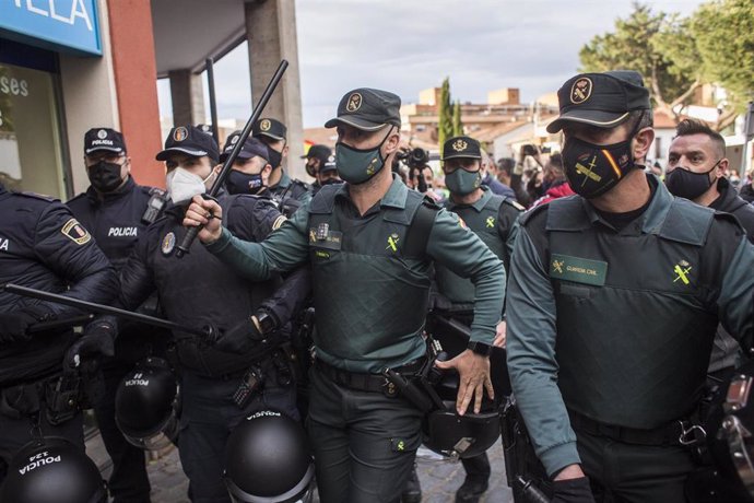 Un grupo de agentes vigila y se protege durante un mitin de Vox, a 21 de abril de 2021, en Navalcarnero, Madrid (España). 