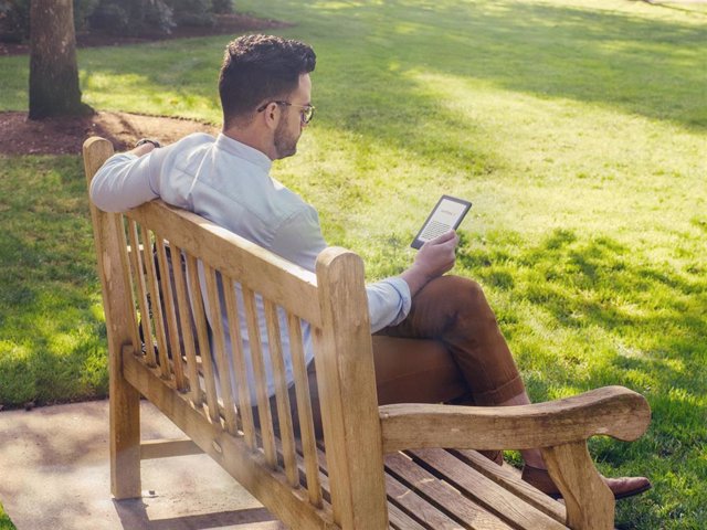Archivo - Hombre leyendo en el parque en un Kindle