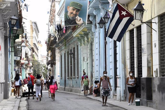 Personas con mascarilla pasean por una calle de La Habana