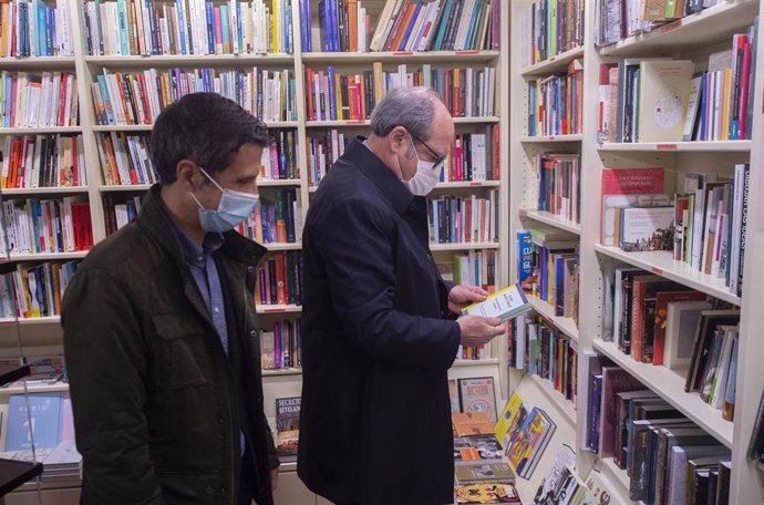 El alcalde de Alcalá de Henares, Javier Rodríguez Palacios (i); y el candidato del PSOE a la Presidencia de la Comunidad de Madrid, Ángel Gabilondo (d), observan un libro en un establecimiento durante su visita por Alcalá de Henares, a 22 de abril de 20