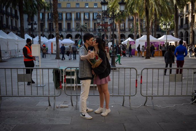 Una pareja se echa una foto con un ramo de rosas rojas mientras se besan, en la Plaza Real de Barcelona en el día de Sant Jordi, a 23 de abril de 2021, en Barcelona, Catalunya, (España)