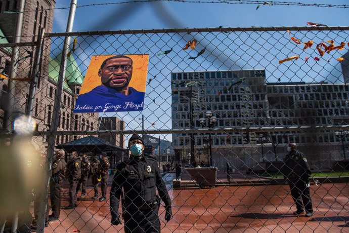 02 April 2021, US, Minneapolis: Police officers remove the photos and locks from the fencing outside the Hennepin County Courthouse, where the trial of a former Minneapolis police officer Derek Chauvin in the death of George Floyd take place. Protestors