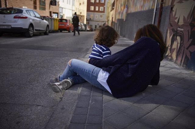 Una mujer junto a una niña pequeña en la calle.