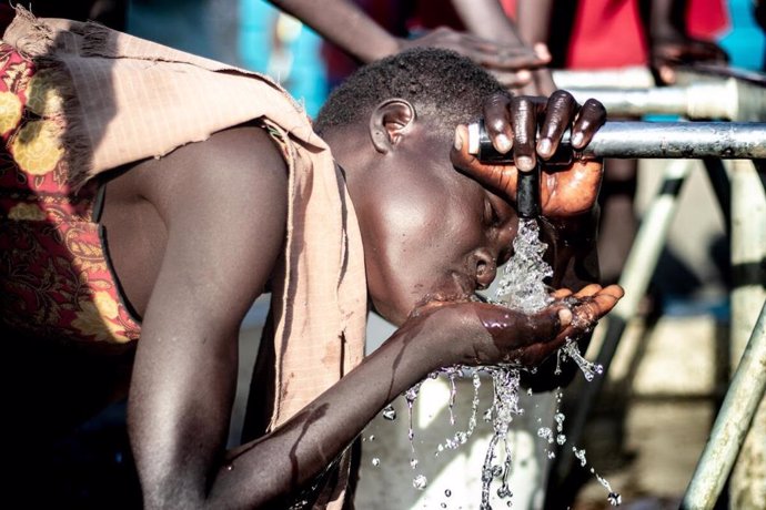 Una persona bebe agua de una fuente