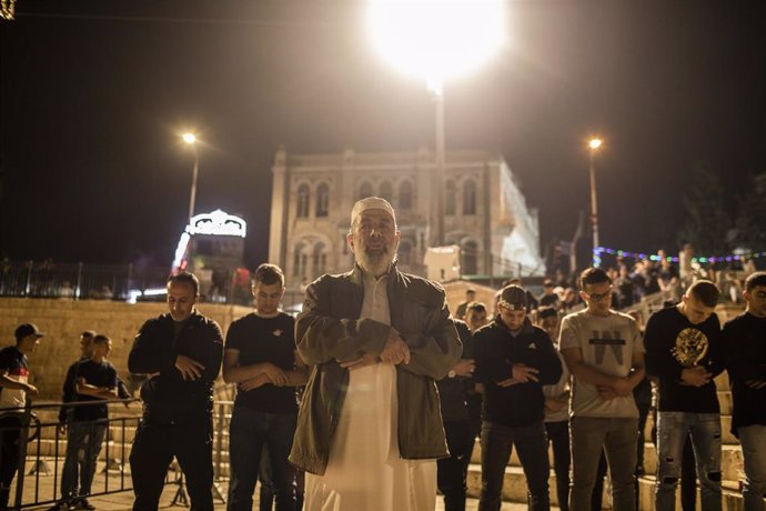 Musulmanes palestinos rezando junto a la Puerta de Damasco de la Ciudad Vieja de Jerusalén a la caída de la noche durante el Ramadán