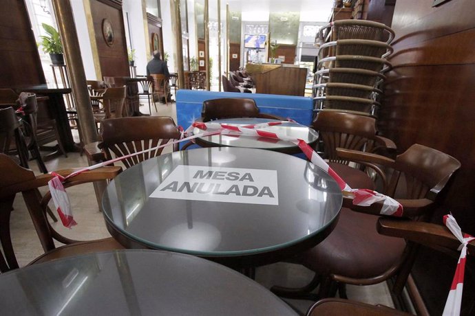 Una mesa del interior de un bar tachada con una cinta de prohibición y un cartel en el que se lee: "Mesa anulada", el día en que entran en vigor nuevas medidas en la hostelería, en Vigo, Pontevedra, Galicia, (España). La Xunta ha decretado desde este vi