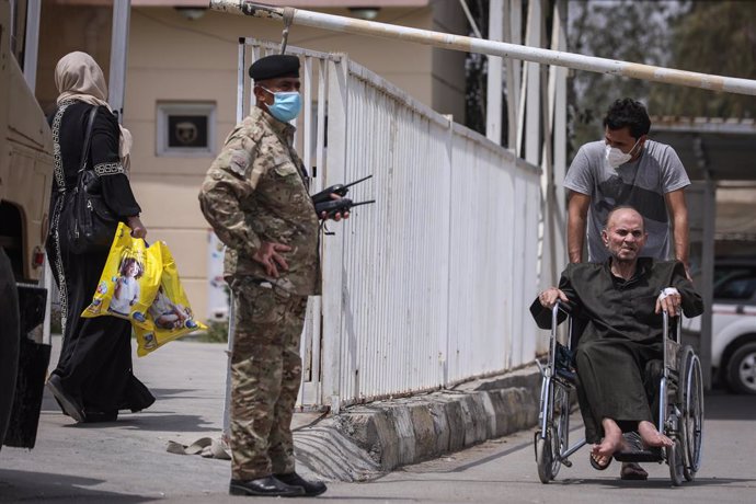 25 April 2021, Iraq, Baghdad: Amember of Iraqi Security forces stands guard outside Ibn al-Khatib Hospital, where a fire broke out early Sunday. According to the Iraqi Interior Ministry, 82 people died and some 110 others were injured in the early Sund