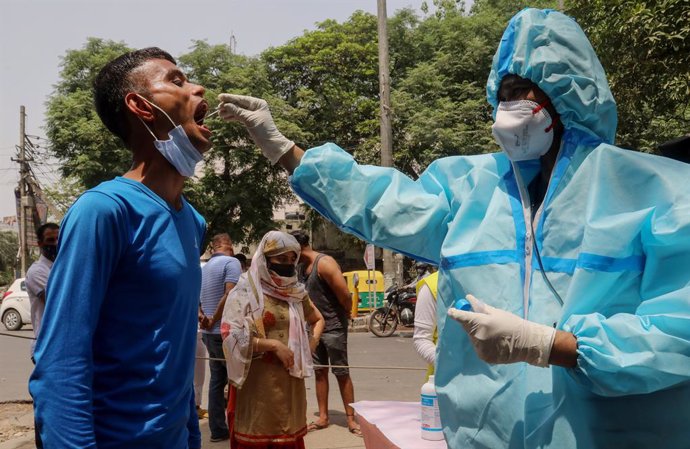15 April 2021, India, New Delhi: A healthcare worker in protective suit collects a mouth swab sample from a man for a COVID-19 RT-PCR test outside the DT City Centre Mall. Photo: Naveen Sharma/SOPA Images via ZUMA Wire/dpa