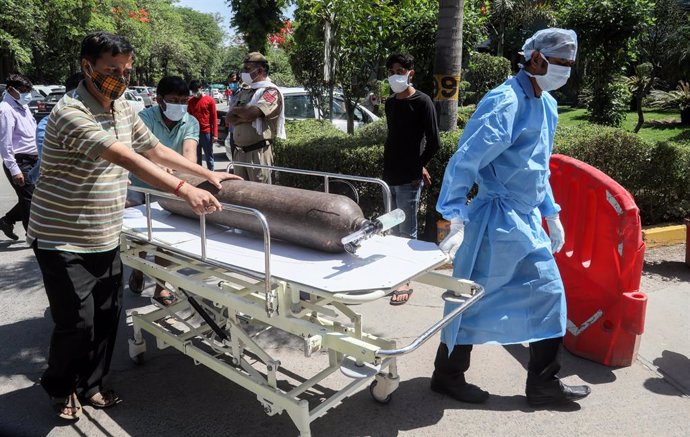 Trabajadores sanitarios entran con una bombona de oxígeno en un hosptal de India en medio de la pandemia de coronavirus