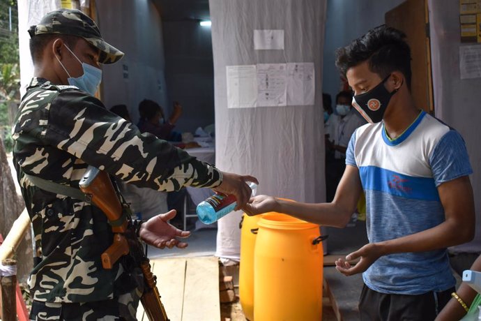 Un personal del Ejército de India suministra gel desinfectante a un joven.