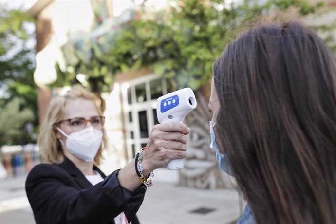 Archivo - Una profesora le toma la temperatura a una alumna, foto de recurso